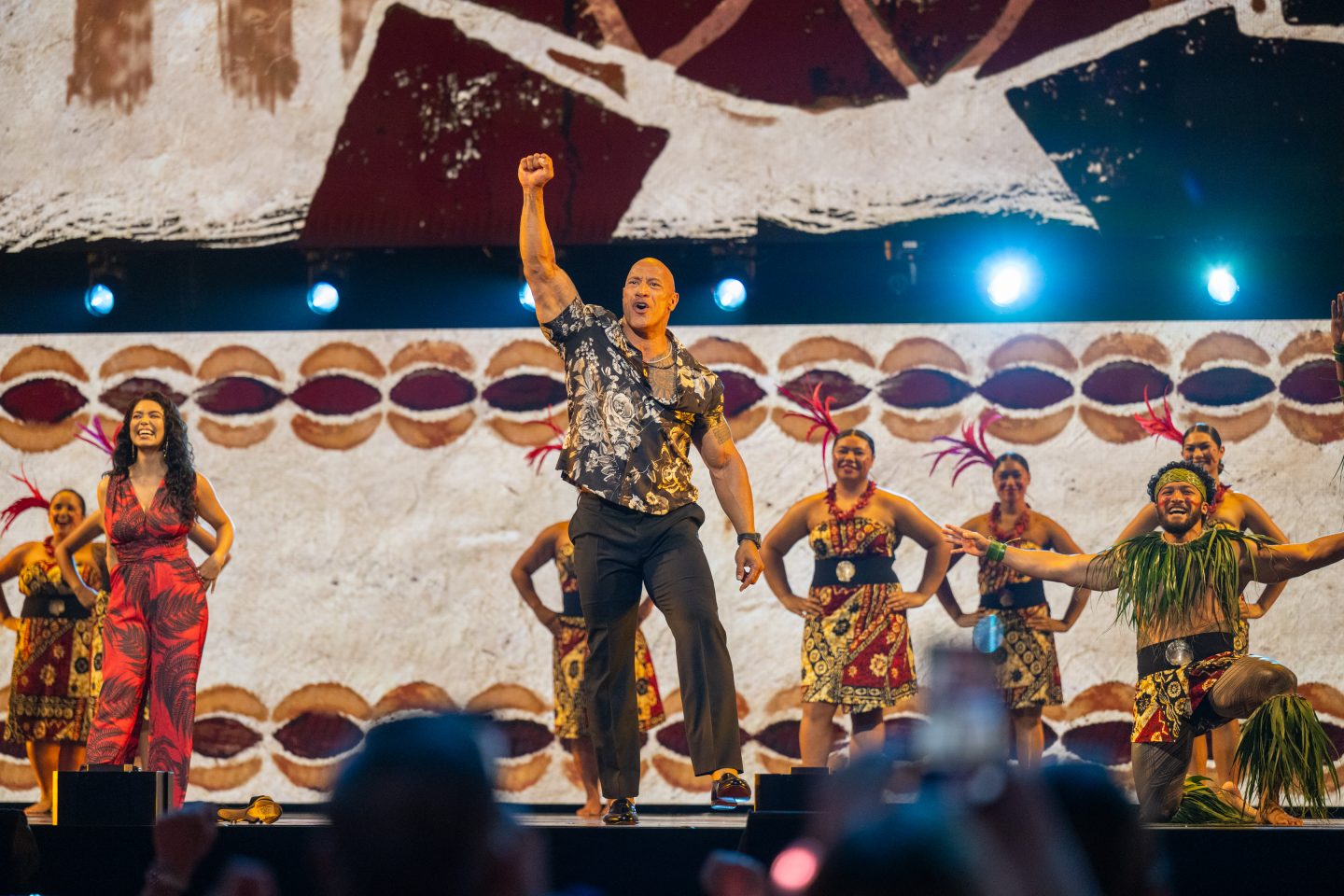 Actor Dwayne Johnson raises his fist as part of a colorful performance celebrating Moana 2 at D23: The Ultimate Disney Fan Event